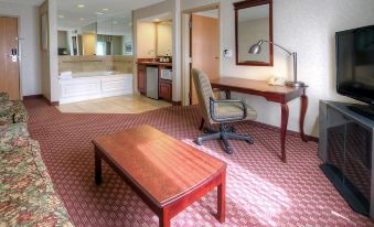 a hotel room with a desk , chair , and coffee table in the corner of the room at Hampton Inn Billings