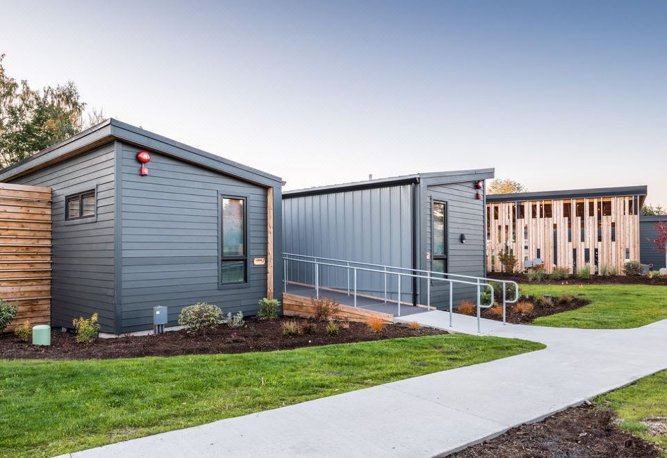 a modern house with a gray exterior and red accents is surrounded by green grass and flowers at Lodges on Vashon