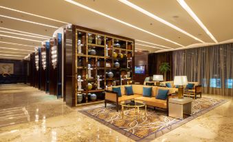 A lobby with large windows and modern furniture in the center, alongside an elegant chandelier at the International Trade City, Yiwu - Marriott Executive Apartments
