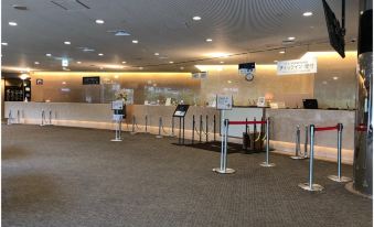 an empty airport check - in counter with multiple signs , as well as a red rope barrier leading to the baggage claim area at Naeba Prince Hotel