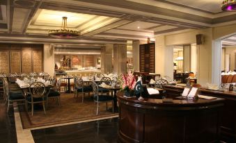 a restaurant with a wooden bar and dining tables , where several people are seated and enjoying their meals at Pearl Continental Hotel, Lahore