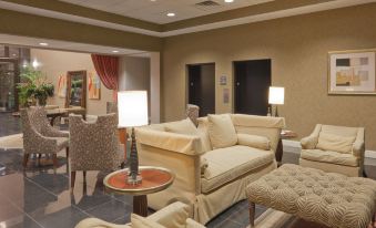 a cozy living room with a couch , chairs , and ottomans arranged around a dining table at Holiday Inn Carbondale-Conference Center