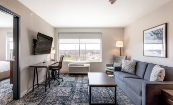 a modern living room with a gray couch , blue rug , and a large window overlooking a city at Four Points by Sheraton Elkhart