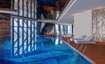 The interior of the hotel includes a spacious pool with blue water and floor-to-ceiling windows providing a scenic view at Element Kuala Lumpur