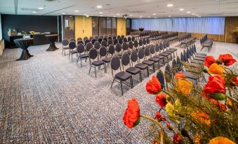 a large conference room with rows of chairs arranged in a semicircle , ready for a meeting at Fletcher Wellness-Hotel Leiden