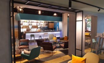 a modern lounge area with various seating options , including couches and chairs , as well as a bar at Novotel le Mans
