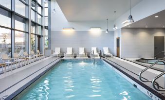 an indoor swimming pool surrounded by lounge chairs , with several people enjoying their time in the pool at Element Vancouver Metrotown