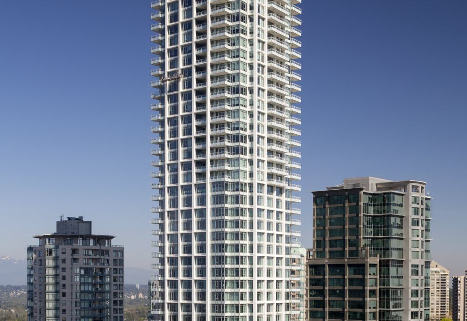 a tall white building with many windows is surrounded by other buildings in a city at Element Vancouver Metrotown