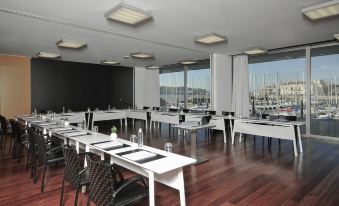 a large conference room with white tables and chairs , a wooden floor , and a view of the ocean at Altis Belem Hotel & Spa, a Member of Design Hotels