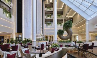 a modern , open - air restaurant with large columns and a circular sculpture hanging from the ceiling at Movenpick Hotel Bahrain