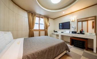a cozy bedroom with a large bed , a tv on the wall , and a round window at Incheon Airport Hotel