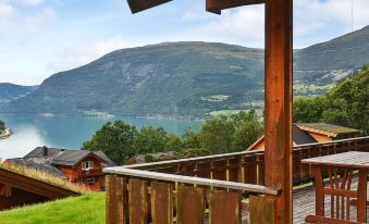 a wooden house with a large deck overlooking a beautiful lake and mountains in the background at Olden