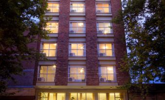 a tall building with many windows and a balcony is lit up at night , surrounded by trees at Hotel Royal