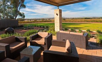 a patio with several chairs and a couch , situated in a grassy field near a golf course at The Louise