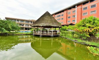 a serene pond surrounded by lush greenery , with a gazebo and a building in the background at Gran Hotel de Lago - El Coca