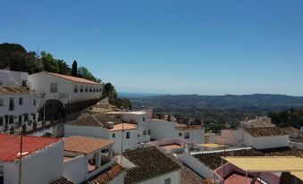 a hillside town with white buildings , red roofs , and a view of the ocean in the distance at Casa del Sol