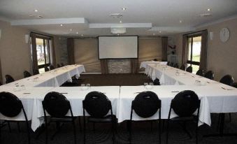 a conference room set up for a meeting , with chairs arranged in rows and a projector screen on the wall at Zig ZAG Motel & Apartments