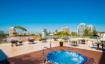 a rooftop patio with a hot tub surrounded by tables and chairs , providing a relaxing atmosphere at Greenmount Beach House