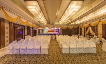 a large banquet hall with rows of white chairs arranged in a symmetrical fashion , ready for an event at The Regenza by Tunga