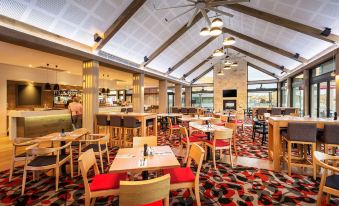 a large , well - lit restaurant with multiple dining tables and chairs , as well as a bar area at Quest Wodonga