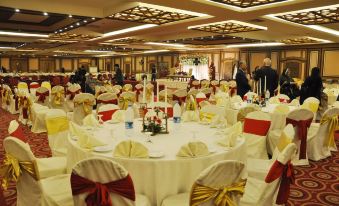 a large banquet hall with multiple round tables covered in white tablecloths and set for a formal event at Pearl Continental Hotel, Lahore