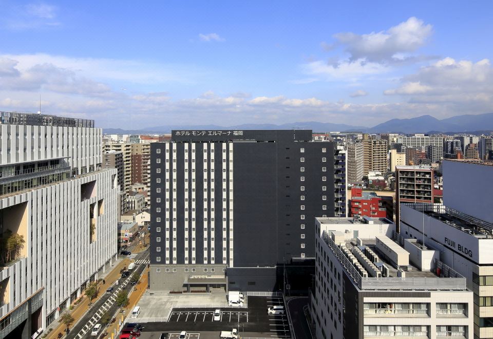 a city skyline with a tall building in the foreground , surrounded by other buildings and skyscrapers at Hotel Monte Hermana Fukuoka