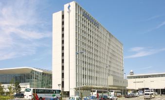 a large white building with a blue logo on top , surrounded by several cars and buses at Centrair Hotel