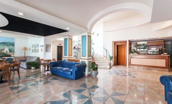 a hotel lobby with a blue couch , chairs , and a staircase leading to the second floor at Hotel Los Angeles