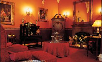 a large room with red carpet and red walls , featuring several paintings and a fireplace at Lumley Castle Hotel
