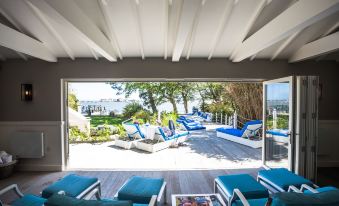 a spacious outdoor patio with multiple lounge chairs and a large window offering a view of the ocean at Harbour Hotel & Spa Christchurch