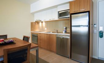 a modern kitchen with stainless steel appliances , including a refrigerator , oven , and microwave , as well as a dining table at Quest Bendigo Central