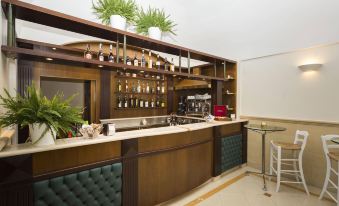 a modern bar with wooden counter , green stools , and various bottles of alcohol on display at Hotel Cavaliere