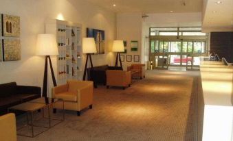 a modern hotel lobby with multiple chairs and tables , as well as several potted plants at Travelodge Maidenhead Central