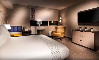 a hotel room with a king - sized bed , a flat - screen tv mounted on the wall , and a desk at GLo Best Western Kanata Ottawa West
