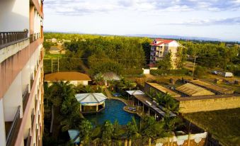 a resort with a large swimming pool surrounded by buildings and trees , as well as a view of the ocean at Rainbow Ruiru Resort