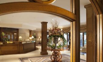 a hotel lobby with a reception desk , large wooden columns , and a circular mirror hanging on the wall at Auberge du Jeu de Paume
