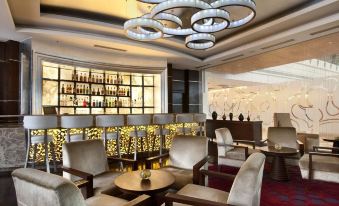 a modern bar with a circular chandelier hanging from the ceiling , surrounded by comfortable seating and bottles of wine at Hyatt Centric Janakpuri New Delhi