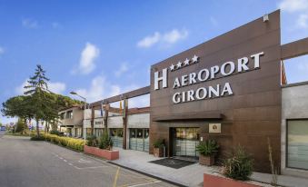 "the exterior of the hilton hotel , named "" aeroport girona "" in spanish , with its name written in cursive above the entrance" at Salles Hotel Aeroport de Girona
