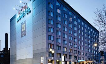"a large , modern hotel building with the name "" moya "" on it , surrounded by snow and trees at dusk" at Novotel Montreal Center