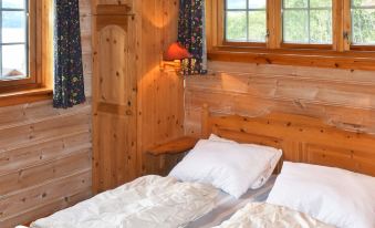 a bedroom with wooden walls and a bed with white sheets and pillows , next to a window at Olden