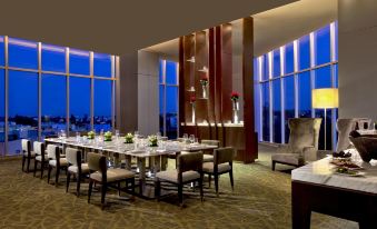 a luxurious restaurant with a large dining table surrounded by chairs , and a view of the ocean through a large window at The Westin Guadalajara