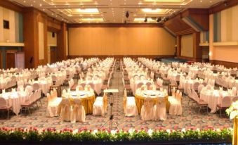 a large banquet hall is set up for a formal event , with tables and chairs arranged in an orderly fashion at Thumrin Thana Hotel