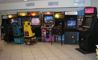 a room filled with various arcade games , including video games and pinball machines , along with yellow tickets on a black cart at Aquarius Vacation Club at Boqueron Beach Resort