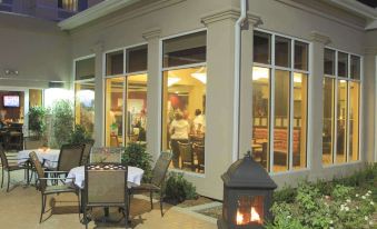 a patio area with several chairs and tables , as well as a fire pit in the background at Hilton Garden Inn Clovis