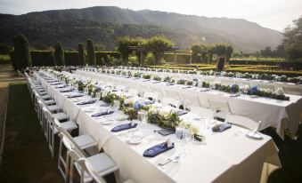 a long table with white linens and blue napkins is set up for an outdoor event at Bernardus Lodge & Spa
