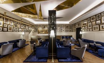 a modern , luxurious living room with gold walls and blue furniture , including chairs , couches , and ottomans at The Oberoi Grand Kolkata