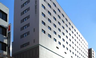 a tall building with many windows is situated next to a street and another building at Numazu River Side Hotel