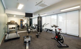 a well - equipped gym with various exercise equipment , including treadmills and weight machines , under a large window at Quest Cannon Hill