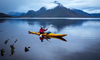 a man in a yellow kayak is paddling on a calm lake with snow - capped mountains in the background at City View Motel