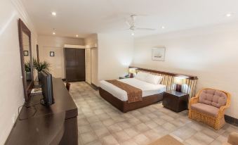 a modern hotel room with a large bed , white walls , and wooden furniture , including a desk , chairs , and a tv at Karma Rottnest